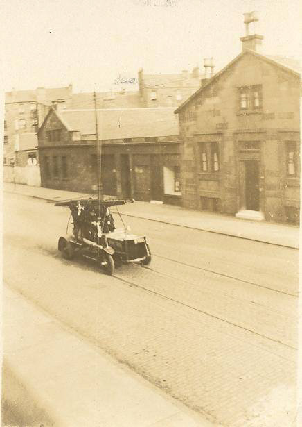 Sepia photo of Nithsdale Street with a very old-fashioned fire engine driving up the road.