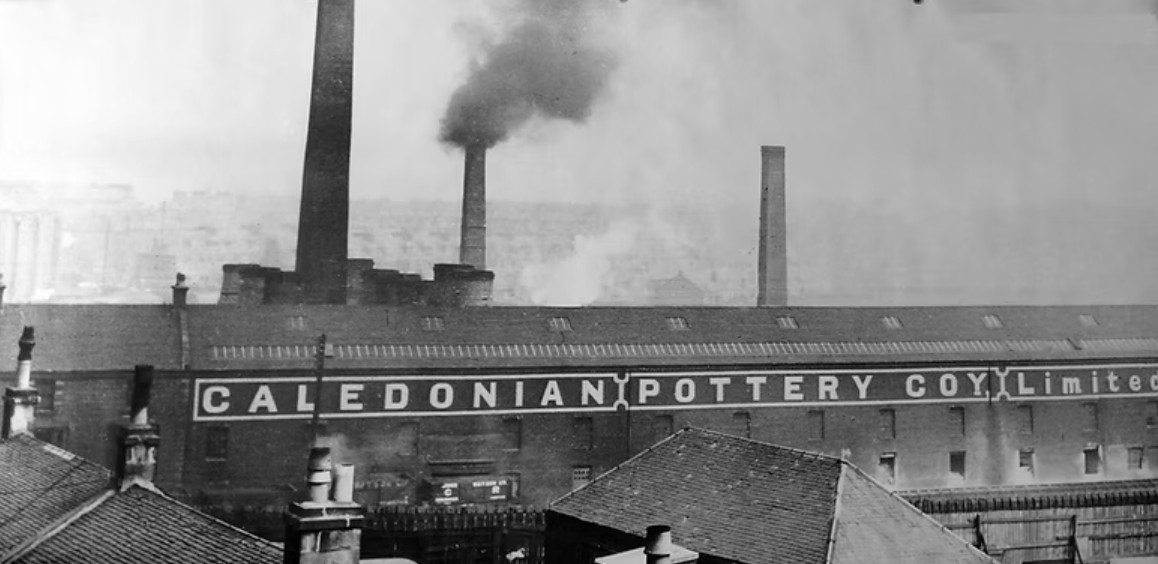 Large factory with company name, and three smokey chimneys