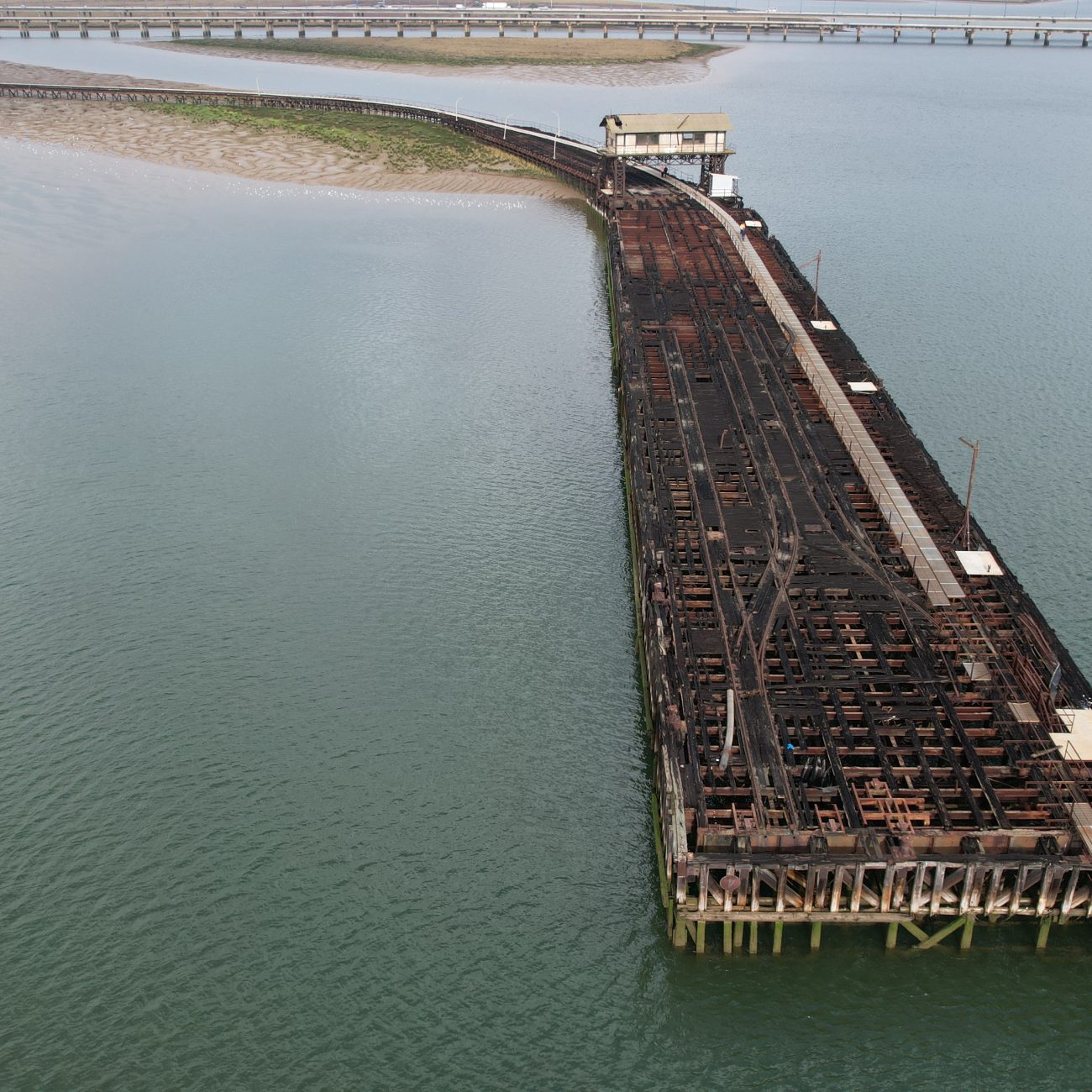 Derelict long pier stretches out into the river