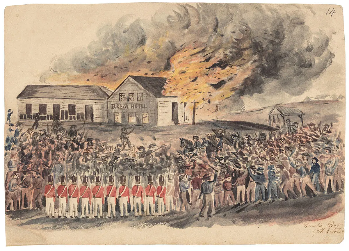 Wooden building on fire while miners and soldiers stand by to watch