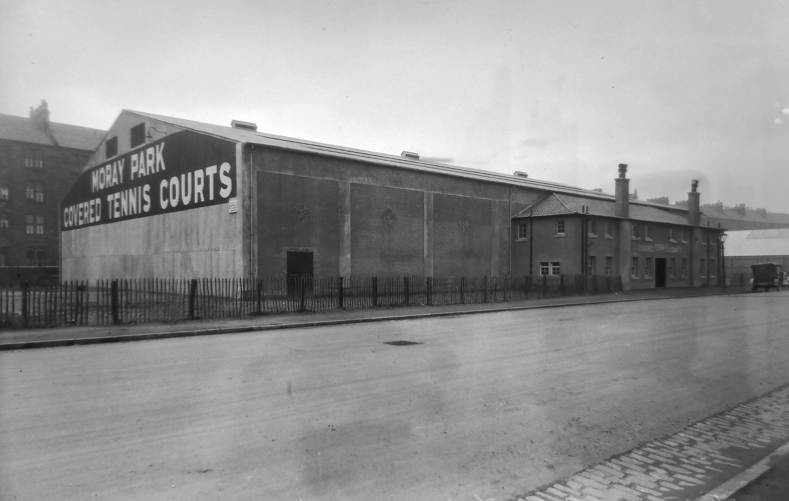 Large warehouse with name on side, and a more ornate office building at the front