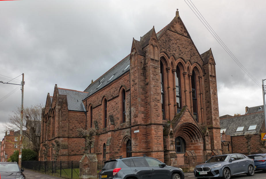 Imposing red sandstone church, early English Gothic style, tall thin windows and prominent buttresses