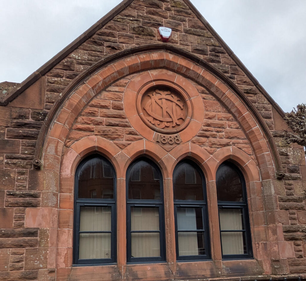 Adjacent hall in similar style with roundel above window