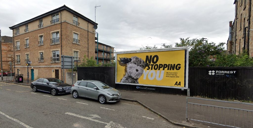 Modern flats and an advertising hoarding on the site of the former Regent Park Motor Garage, from Google Street View 2022. 