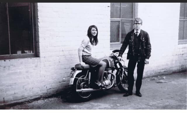 Man beside motorbike, women sitting on the saddle